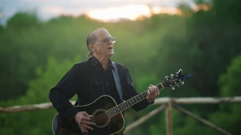 Joe Cerisano with a guitar in Tuscany